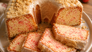 Homemade Strawberry Crunch Pound Cake with vanilla glaze and buttery strawberry cookie crumble topping sliced on a white cake stand.