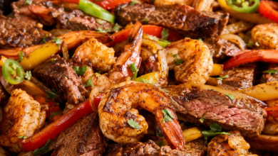 Steak and shrimp fajitas with seared beef, shrimp, bell peppers, onions, jalapeños, and cilantro in a cast-iron skillet