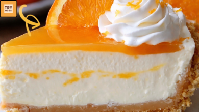 Slice of creamy orange creamsicle cheesecake with graham cracker crust topped with whipped cream and fresh orange slice