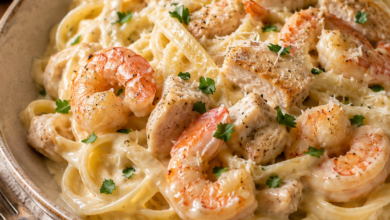 Creamy shrimp and chicken fettuccine Alfredo served in a rustic ceramic bowl with Parmesan and fresh parsley.