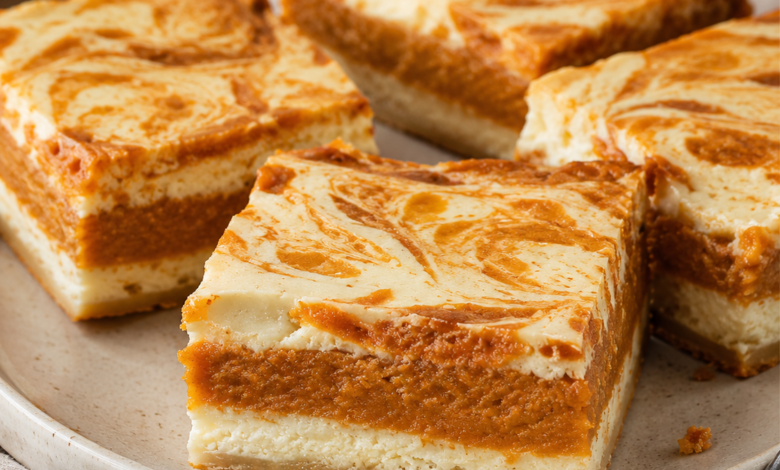 Sweet potato cheesecake brownies with creamy cheesecake layers, orange sweet potato filling, and a marbled top on a ceramic plate.