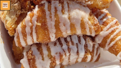 Golden brown sweet potato hand pies stacked with powdered sugar glaze on top