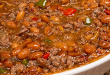 saucy loaded baked beans with ground beef in rich sauce baked in white dish
