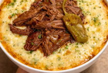 Mississippi pot roast served over creamy cheesy grits with pepperoncini on top