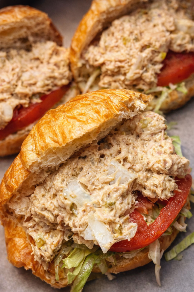 creamy tuna egg salad sandwich on croissant with lettuce and tomato
