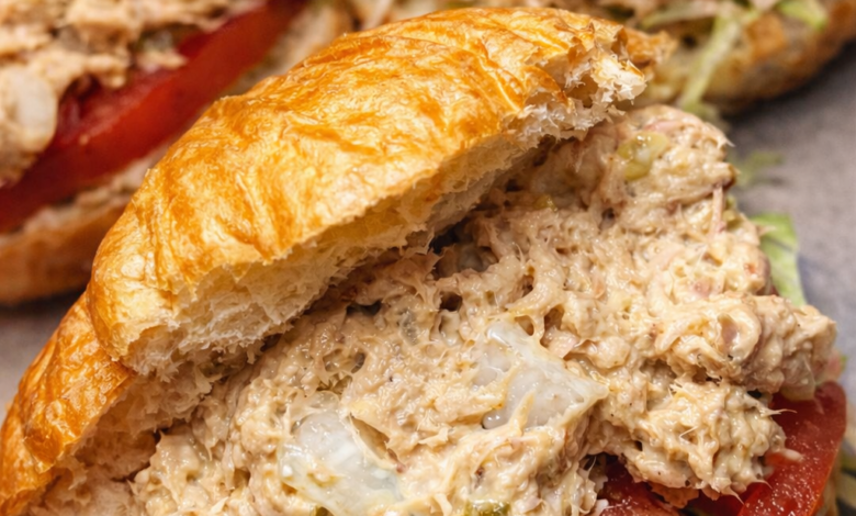 creamy tuna egg salad sandwich on croissant with lettuce and tomato