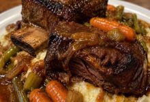 Braised beef short ribs served over creamy mashed potatoes with carrots, celery, and rich red wine gravy.
