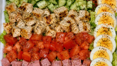 Restaurant-style classic Cobb salad with grilled chicken, bacon, ham, cheddar cheese, eggs, cucumbers, tomatoes, and romaine lettuce.