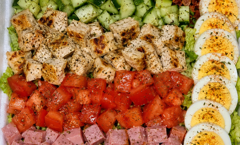 Restaurant-style classic Cobb salad with grilled chicken, bacon, ham, cheddar cheese, eggs, cucumbers, tomatoes, and romaine lettuce.