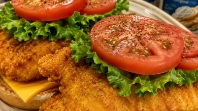 Crispy fried catfish sandwich with American cheese, lettuce, tomato, and Cajun tartar sauce on a toasted bun.