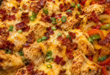 Loaded bacon ranch chicken skillet with melted cheddar, mozzarella, crispy bacon, bell peppers, and green onions in a cast iron pan.